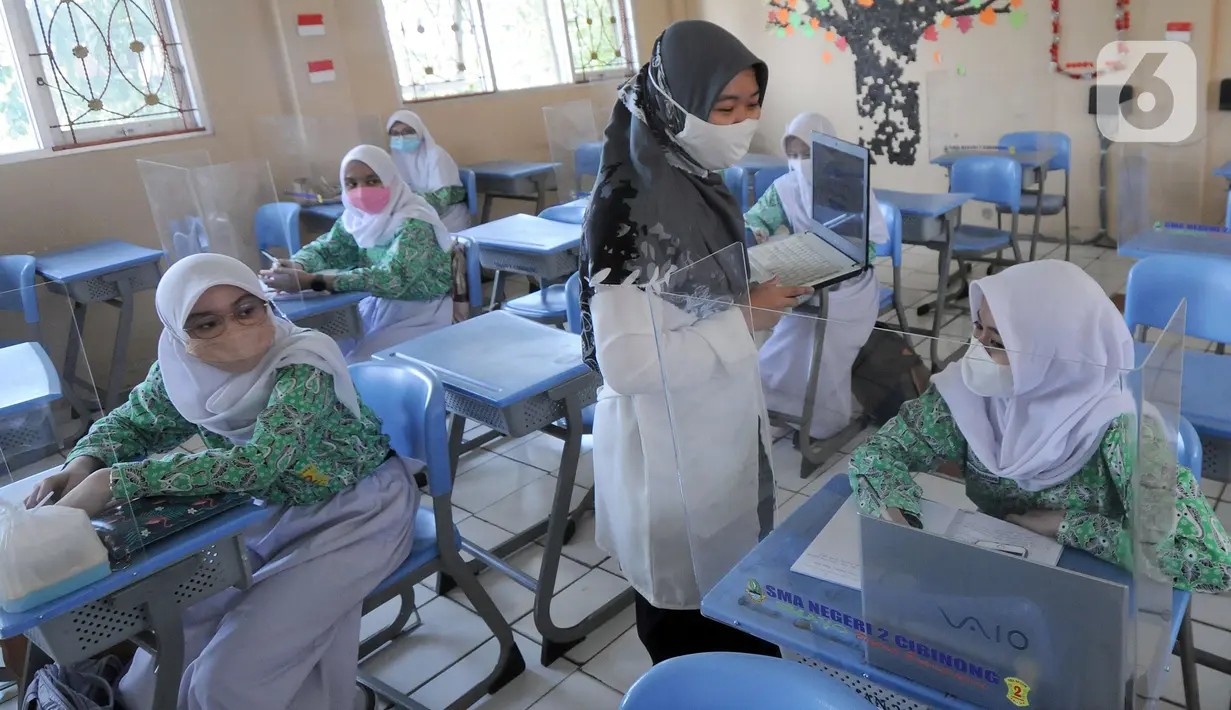 Guru melakukan kegiatan belajar tatap muka dengan penerapan protokol kesehatan COVID-19 di SMAN 2 Cibinong, Kabupaten Bogor, Jawa Barat, Rabu (17/3/2021). Sebanyak 170 sekolah di Kabupaten Bogor mulai menggelar uji coba pembelajaran secara tatap muka hingga 10 April 2021. (merdeka.com/Arie Basuki)