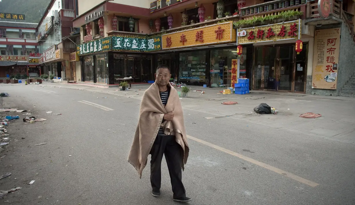 Warga berjalan-jalan setelah tidur di luar rumahnya di Zhangzha, provinsi Sichuan, China barat daya, Kamis (10/8). Ratusan warga memilih menghabiskan malam di luar rumah usai terjadinya gempa 6,5 SR yang menewaskan belasan orang (Nicolas ASFOURI/AFP)