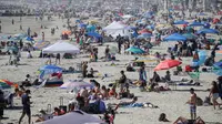 Pengunjung berkumpul di Pantai Newport selama masa pandemi covid-19 di California pada Minggu (24/5/2020). Warga Amerika Serikat mengabaikan pedoman jarak sosial dan memilih berjemur di pantai ketika angka kematian akibat virus corona di negara itu mendekati 100.000 orang. (AP/Marcio Jose Sanchez)