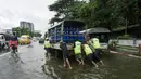 Orang-orang mendorong kendaraan yang mogok di jalan yang banjir di pinggiran Yangon, Myanmar  (17/8/2022). Sebagian besar kotapraja di Yangon dilanda banjir yang menyebabkan kemacetan lalu lintas pada jam-jam sibuk. (AFP/Stringer)