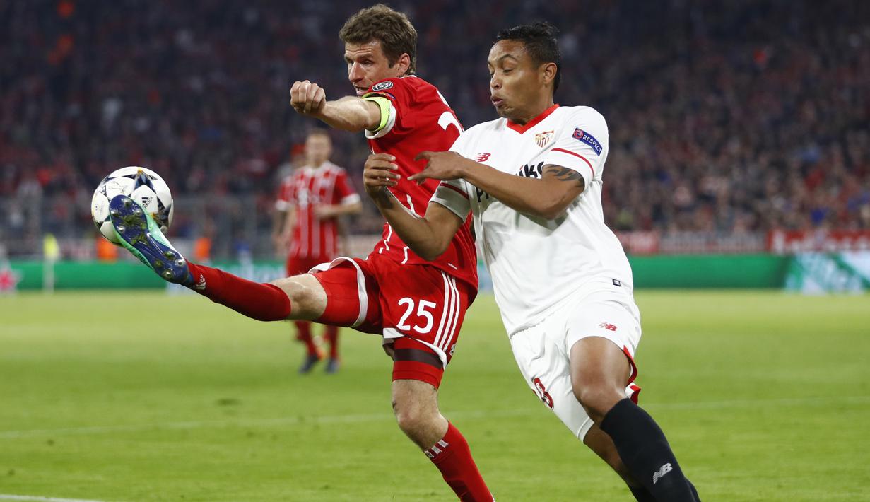 Thomas Mueller (kiri) mencoba menghalau bola dari kejaran pemain Sevilla, Luis Muriel pada leg kedua perempat final Liga Champions di Allianz Arena stadium, Munich, (11/4/2018). Bayern lolos ke semifinal dengan agregat 2-1. (AP/Matthias Schrader)