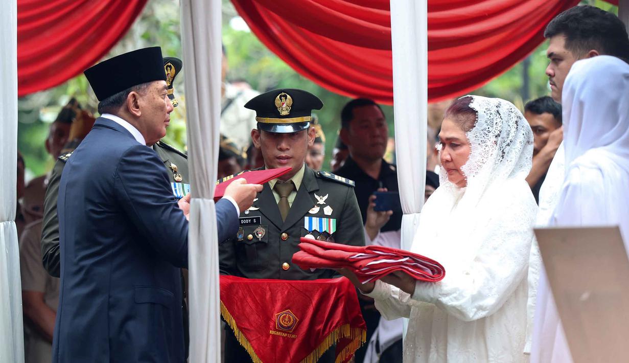 Menteri Pertahanan Sjafrie Sjamsoeddin (kiri) menyerahkan bendera Merah Putih kepada istri Jenderal TNI (Purn) Ryamizard Ryacudu di Taman Makam Pahlawan Nasional, Kalibata, Jakarta, Senin (1/6/2026). (Kapanlagi.com/Budy Santoso)