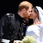 Pangeran Harry mencium istrinya, Meghan Markle di tangga Pintu Barat St George's Chapel, Kastil Windsor, Inggris, Sabtu (19/5). Pangeran Harry dan Meghan Markle telah resmi menikah. (Ben STANSALL/POOL/AFP)