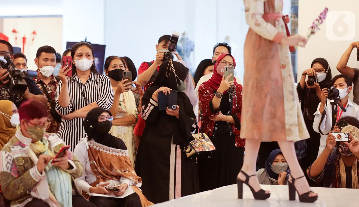 Pengunjung mengabadikan model dengan busana kain serat alami pada Ecoprint Fashion Week 2022 di The Plaza Semanggi, Jakarta, Rabu (06/4/2022). Kegiatan yang berkontribusi terhadap kebangkitan perekonomian merupakan bentuk komitmen LMI pada budaya dengan konsep zero-waste. (Liputan6.com/Fery Pradolo)