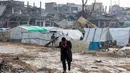 Seorang pria Palestina berjalan di depan tenda-tenda yang didirikan di tengah kehancuran di Beit Hanoun, Jalur Gaza utara pada 12 Februari 2025. (Omar AL-QATTAA/AFP)