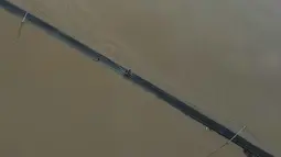 Dalam hitungan jam, air yang semula hanya menggenangi jalan berubah menjadi arus deras yang masuk ke rumah-rumah warga. Tampak foto udara memperlihatkan seorang pengendara yang sedang berkendara di jalan yang terendam banjir di Kangar, negara bagian Perlis, Malaysia utara, pada Jumat 28 November 2025. (Mohd RASFAN/AFP)