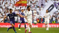 Gelandang Real Madrid, Isco, berusaha melewati bek Valladolid, Javi Moyano, pada laga La Liga di Stadion Santiago Bernabeu, Madrid, Sabtu (24/8). Kedua klub bermain imbang 1-1. (AFP/Gabriel Bouys)
