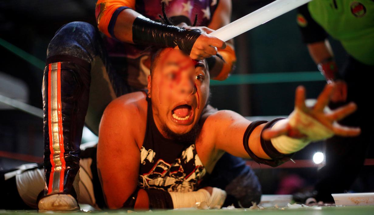 Ekspresi kesakitan seorang pegulat saat wajahnya diserang dengan lampu tabung saat pertandingan gulat ekstrim di Arena Neza di pinggiran Mexico City, Meksiko (28/10). Dalam pertandingan ini pegulat juga boleh menggunakan senjata. (Reuters/ Carlos Jasso)