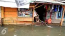 Seorang ibu menguras air yang membanjiri rumahnya dengan menggunakan selang di Kawasan Muara Angke, Jakarta, Rabu (11/1). Banjir ini terjadi hampir setiap hari dalam satu bulan terakhir. (Liputan6.com/Gempur M. Surya)