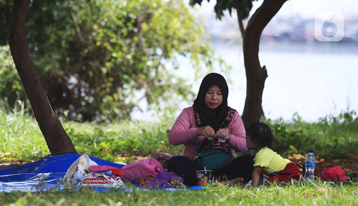 Seorang ibu bersama anaknya piknik di Taman Kota Waduk Pluit di Penjaringan, Jakarta Utara, Minggu (27/12/2020). Taman Kota Waduk Pluit dibuka kembali setelah ditutup pada libur Natal, namun banyak warga yang berwisata tidak menerapkan protokol kesehatan. (Liputan6.com/Johan Tallo)