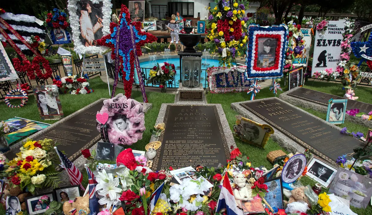 Karangan bunga beserta poster Elvis Presley memenuhi makam sang bintang rock n roll itu di Graceland, Memphis, Tennessee, Selasa (16/8). Elvis Presley menjadi salah satu ikon budaya paling penting di abad ke-20. (AP Photo/Brandon Dill)