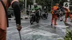 Sejumlah pengendara motor berkendara dengan hati-hati saat anggota Penanganan Prasarana dan Sarana Umum (PPSU) membersihkan tumpahan oli di kawasan Jalan Thamrin, Jakarta, Selasa (4/10/2022). Pembersihan ceceran tumpahan oli tersebut agar pengendara motor tidak terjatuh. (Liputan6.com/Faizal Fanani)