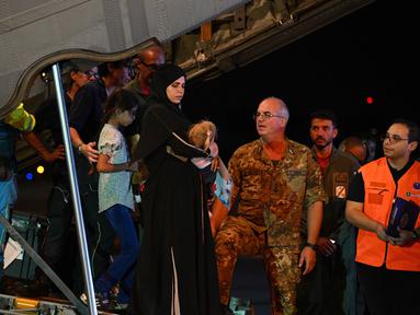 Petugas medis dan tenaga kesehatan menyambut anak-anak Palestina dari Gaza beserta keluarga mereka, setelah pesawat militer Italia C130J dari Israel mendarat pada 14 Agustus 2025 di Bandara Ciampino, Roma. (Andreas SOLARO/AFP)