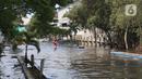 Seorang pejalan kaki menerobos banjir rob di kawasan Pelabuhan Perikanan Samudera Nizam Zachman, Muara Baru, Jakarta, Sabtu (6/11/2021). Banjir rob tersebut disebabkan karena naiknya permukaan air laut. (Liputan6.com/Herman Zakharia)