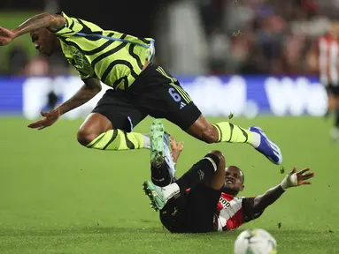 Bek Arsenal Gabriel (kiri) dijegal oleh gelandang  Brentford Frank Onyeka dalam laga putaran ketiga Carabao Cup 2023/2024 di Gtech Community Stadium, Kamis (28/9/2023) dini hari WIB. (AP Photo/Ian Walton)