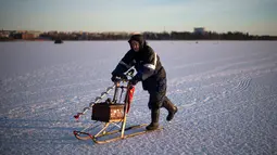 Seorang pria usai memancing di laut Bothnia yang sedang membeku, Vaasa, Finlandia (29/12). Kebiasaan memancing di laut beku merupakan hal menantang yang ditunggu-tunggu oleh sebagian warga setempat. (AFP PHOTO/Olivier Morin)