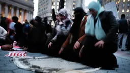 Wanita muslim menggelar salat berjemaah sebelum melakukan aksi protes di Manhattan, New York (1/2). Mereka juga mengecam kebijakan Donald Trump terkait larangan imigran dari negara mayoritas muslim masuk ke AS. (AFP/Spencer Platt)
