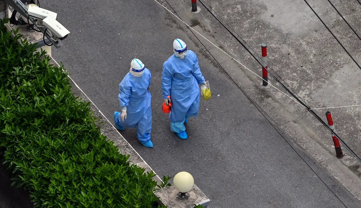 Petugas kesehatan yang mengenakan alat pelindung diri (APD) berjalan di jalan setelah meninggalkan lingkungan saat lockdown akibat virus corona COVID-19 di Distrik Jing'an, Shanghai, China, Sabtu (16/4/2022). (Hector RETAMAL/AFP)