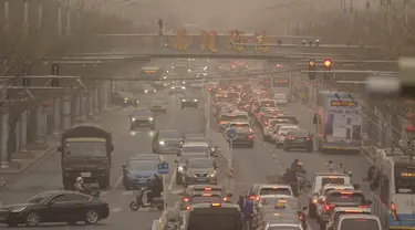 Mobil dan pejalan kaki menyusuri jalan yang diselimuti debu dan kabut di Beijing, Jumat, 10 Maret 2023. Pencakar langit menghilang ke dalam kabut dan kualitas udara anjlok saat ibu kota China diselimuti badai debu dan polusi berat. (AP Photo/Mark Schiefelbein)