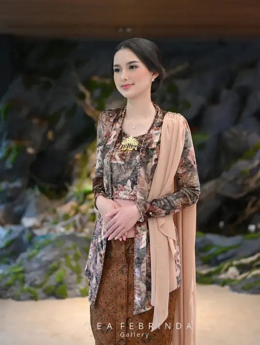 Ayunya Sarah Menzel dibalut kebaya velvet bercorak floral bernuansa kecokelatan. Kebaya ini dihiasi payet-payet yang menambah nuansa manis pada keseluruhan tampilan, selendang, dan korset cokelat muda yang serasi. [Foto: Instagram/deafebrindagallery]