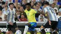 Pemain Brasil, Vinicius Jr, mencoba melepaskan diri dari adangan dua pemain Argentina pada pertandingan Kualifikasi Piala Dunia 2026 Zona Amerika Selatan, Rabu (26/3/2025) pagi WIB. (Luis ROBAYO / AFP)