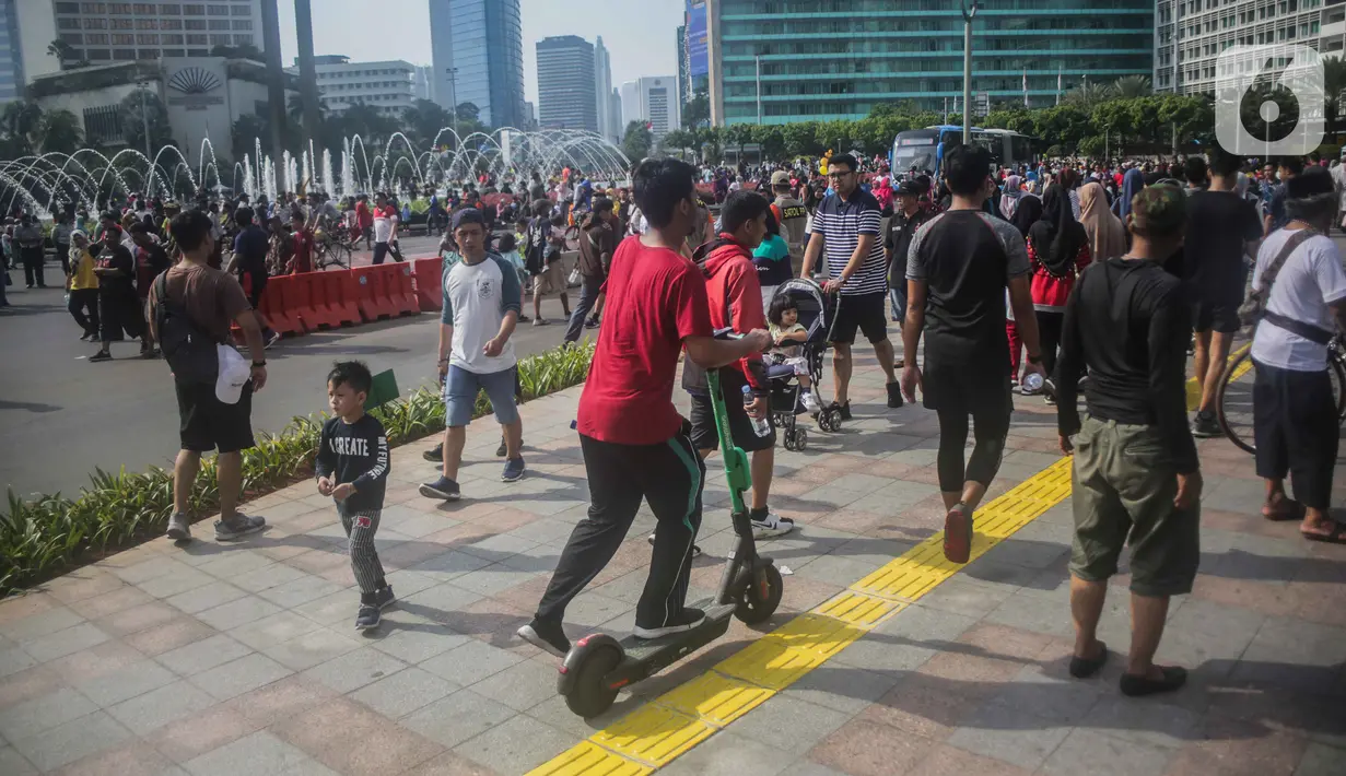 Warga mengendarai skuter listrik saat Car Free Day (CFD) di kawasan Bundaran HI, Jakarta, Minggu (17/11/2019). Skuter listrik dilarang digunakan saat CFD karena dianggap masih menggunakan motor sehingga tak bisa disesuaikan dengan sepeda. (Liputan6.com/Faizal Fanani)