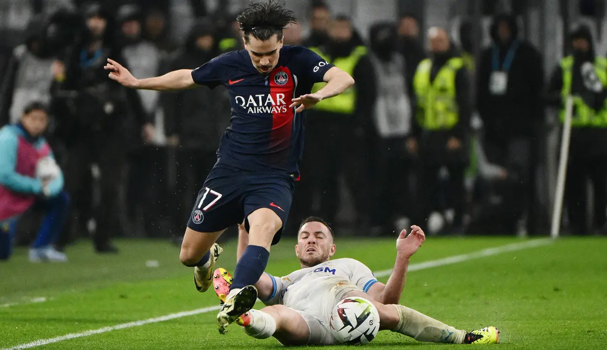 Pemain Paris Saint-Germain, Vitinha, berusaha melewati pemain Marseille, Jordan Veretout, dalam duel pekan ke-27 Ligue 1 2023/2024 di Stade Velodrome, Senin (1/4/2024). (AFP/Christophe Simon)