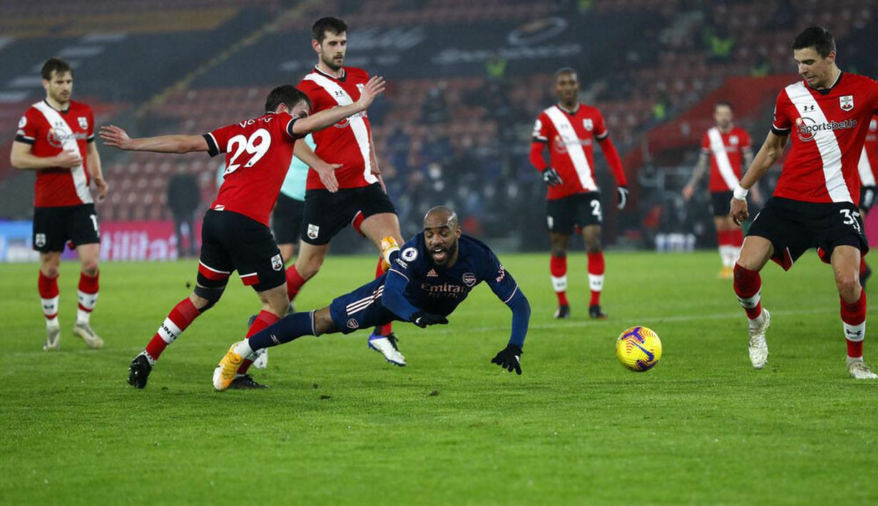 Penyerang Arsenal, Alexandre Lacazette, terjatuh saat melawan Southampton pada laga Liga Inggris di Stadion St Mary, Selasa (26/1/2021). Arsenal menang dengan skor 3-1. (AP/Frank Augstein, Pool)