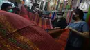Pembeli melihat-lihat kain ulos di pasar proyek Senen, Jakarta, Kamis (21/10/2021). Sejak status PPKM turun menjadi level 2, pengunjung ramai mendatangi toko membeli kain ulos untuk upacara pernikahan adat dengan kisaran harga dari Rp. 500.000 hingga jutaan rupiah. (merdeka.com/Imam Buhori)