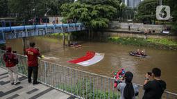Fanani)
Warga menyaksikan pembentangan bendera Merah Putih di aliran kali
Ciliwung di kawasan Sudirman, Jakarta, Minggu (22/8/2021). Pembentangan atau pengibaran bendera Merah Putih tersebut dilaksanakan untuk memperingati HUT ke-76 RI. (Liputan6.com/Faizal Fanani)