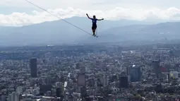 Aksi nekat Alexander Schultz berjalan di antara dua gedung tertinggi Mexico City menggunakan tali pada ketinggian 246 meter di Meksiko, 4 Desember 2016. Schultz butuh lima kali usaha menaklukkan tali sepanjang 217 meter itu. (REUTERS/Stringer)