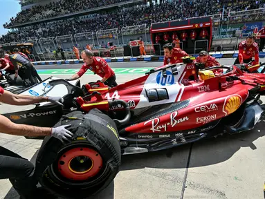 Mekanik mendorong mobil pembalap Ferrari asal Inggris, Lewis Hamilton, di pit saat sesi latihan pertama Formula Satu Grand Prix China di Sirkuit Internasional Shanghai pada 21 Maret 2025. (HECTOR RETAMAL/AFP)