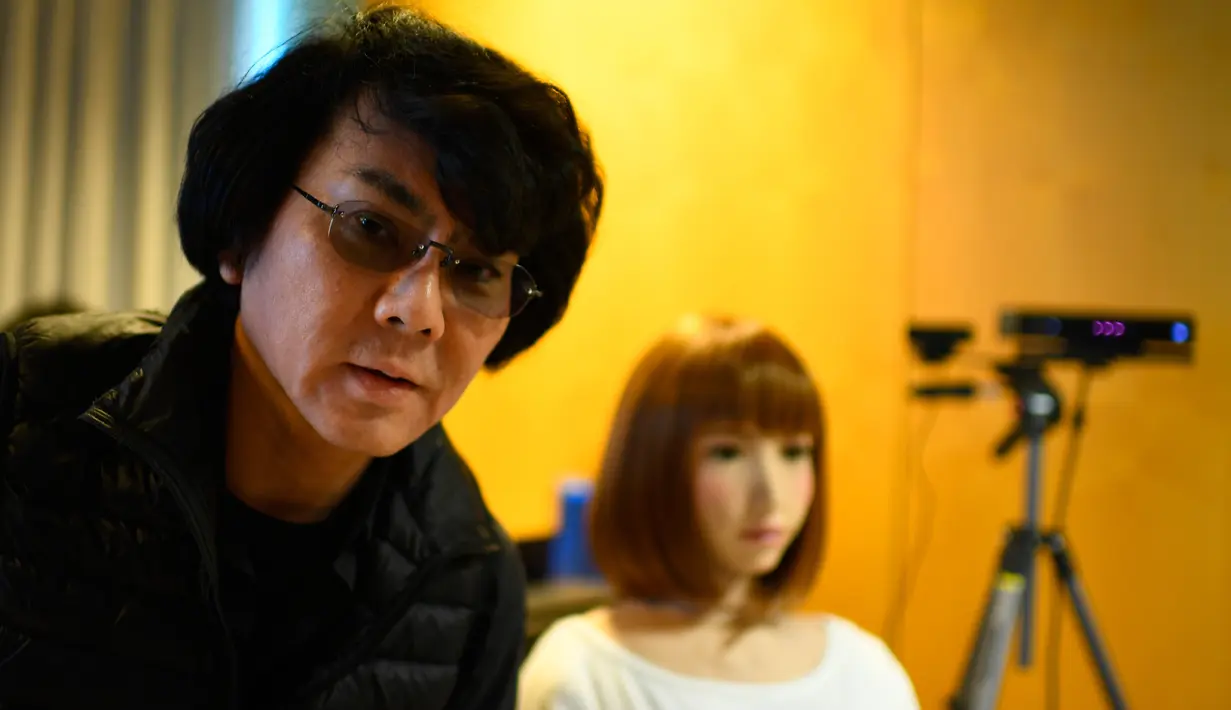 Insinyur robot Jepang Hiroshi Ishiguro berpose di sebelah robotnya yang bernama Erica selama presentasinya di Konferensi Internasional IROS 2018 di Madrid, Spanyol (5/10). (AFP Photo/Gabriel Bouys)
