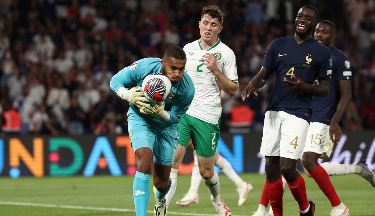 Kiper Timnas Republik Irlandia, Gavin Bazunu berhasil mengamankan bola dari ancaman bek Timnas Prancis, Dayot Upamecano pada laga Grup B Kualifikasi Euro 2024 di Parc des Princes Stadium, Paris, Jumat (8/9/2023) dini hari WIB. (AFP/Franck Fife)
