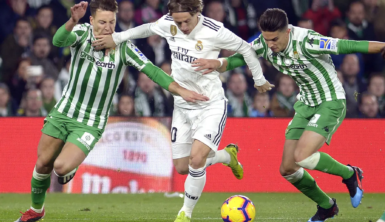 Luka Modric mencoba melewati hadangan pemain Real Betis pada laga lanjutan La Liga Spanyol yang berlangsung di stadion Benito Villamarin, Senin (14/1). Real Madrid menang 2-1 atas Real Betis. (AFP/Cristina Quicler)