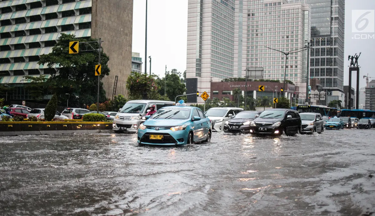 Sejumlah kendaraan melintas menerjang genangan air di kawasan Bunderan HI, Jakarta, Kamis (22/11). Genangan air hujan setinggi 40 cm tersebut disebabkan hujan deras yang melanda Jakarta pada siang hari. (Liputan6.com/Faizal Fanani)