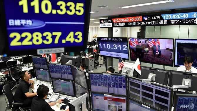 Pasar bursa Tokyo juga mengamati momen bersejarah pertemuan Donald Trump dan Kim Jong-un di Singapura. (Photo: AFP/Kazuhiro Nogi)