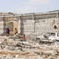 Orang-orang berjalan di sebelah rumah yang hancur dan puing-puing mobil menyusul serangan oleh militan Al-Shabaab selama penyerangan ke kantor polisi di pinggiran Mogadishu, Somalia (16/2/2022). (AFP/Hassan Ali Elmi)