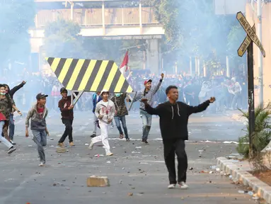 Massa melemparkan batu ke arah barisan polisi dalam unjuk rasa di sekitaran Gedung DPR RI, Jakarta, Senin (30/9/2019). Kericuhan pecah lantaran massa yang kebayakan terdiri dari pelajar tersebut berusaha masuk ke area depan DPR. (Liputan6.com/Angga Yuniar)
