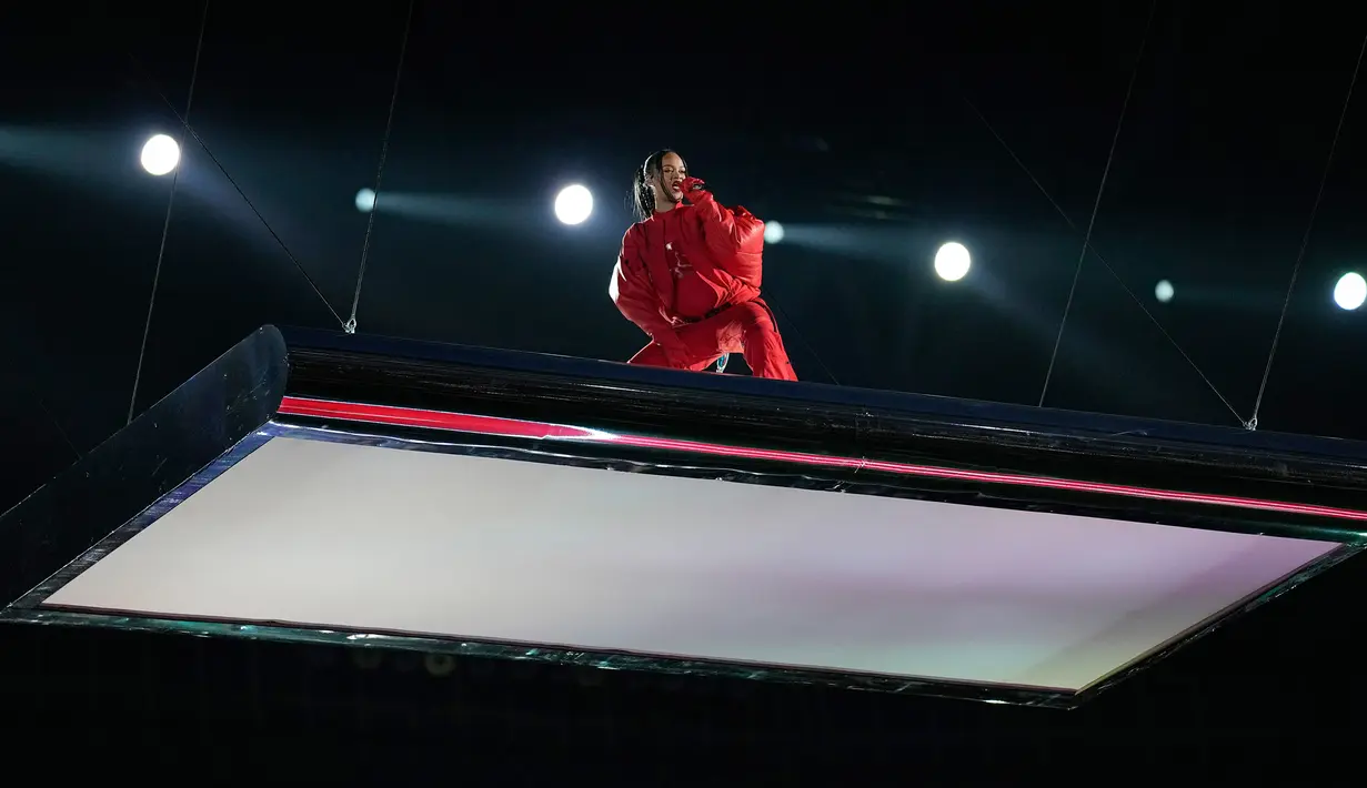 Rihanna tampil pada acara turun minum pertandingan sepak bola NFL Super Bowl 57 antara Kansas City Chiefs dan Philadelphia Eagles di Glendale, Arizona, Amerika Serikat, 12 Februari 2023. Rihanna mengenakan jumpsuit Loewe, perhiasan Messika, dan MM6 Maison Margiela x Salomon Cross High Sneakers seharga USD 415 atau setara Rp 6,3 juta. (AP Photo/Abbie Parr)
