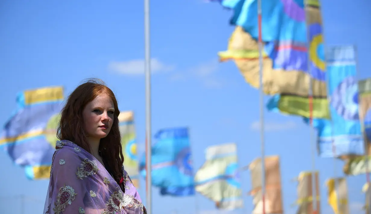 Seorang wanita menonton festival Glastonbury di desa Pilton, di Somerset, Inggris Barat Daya (22/6/2022). Pandemi virus corona memaksa penyelenggara untuk membatalkan acara dua tahun terakhir, dan mereka yang pergi tahun ini menghadapi perjalanan yang sulit melawan tiga hari pemogokan kereta api besar di seluruh negeri. (AFP/Andy Buchanan)