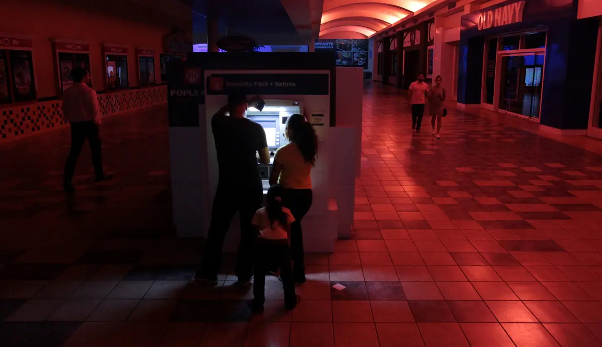Warga menggunakan mesin ATM di pusat perbelanjaan ketika pemadaman listrik di San Juan, Puerto Rico, Rabu (21/9). Kebakaran yang terjadi di pembangkit listrik Puerto Rico menyebabkan 1,5 juta penduduk pulau itu hidup tanpa listrik. (REUTERS/Alvin Baez)