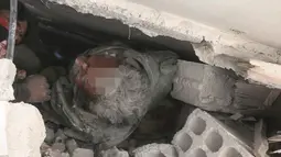 Pria terjebak di bawah reruntuhan bangunan usai serangan udara pasukan pemerintah di Ghouta Timur, Damaskus, Suriah, Selasa (20/2). Pasukan pemerintah diduga bersiap melakukan serangan darat ke lokasi tersebut. (Syrian Civil Defense White Helmets via AP)