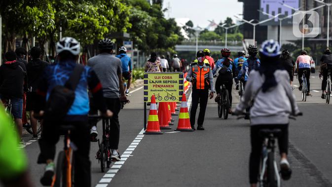 Papan pengumuman uji coba pembatas jalur sepeda permanen terlihat di kawasan Sudirman, Jakarta, Minggu (28/2/2021). Uji coba berlangsung selama tahap penyempurnaan jalur sepeda permanen yang ditargetkan rampung akhir Maret 2021. (Liputan6.com/Johan Tallo)