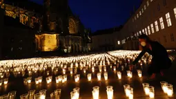 Seorang wanita menyalakan lilin untuk memperingati para korban pandemi virus corona COVD-19 di Kastil Praha, Praha, Republik Ceko, Senin (10/5/2021). Republik Ceko melonggarkan pembatasan terkait COVID-19 secara besar-besaran kendati hampir 30 ribu orang telah meninggal. (AP Photo/Petr David Josek)