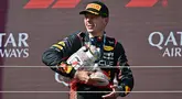 Pembalap Red Bull Racing, Max Verstappen berjalan meninggalkan podium sambil membawa trofinya yang pecah pada Formula 1 GP Hungaria di Sirkuit Hungaroring, Mogyorod, Hungaria, Minggu (23/07/2023). (AFP/Attila Kisbendek)
