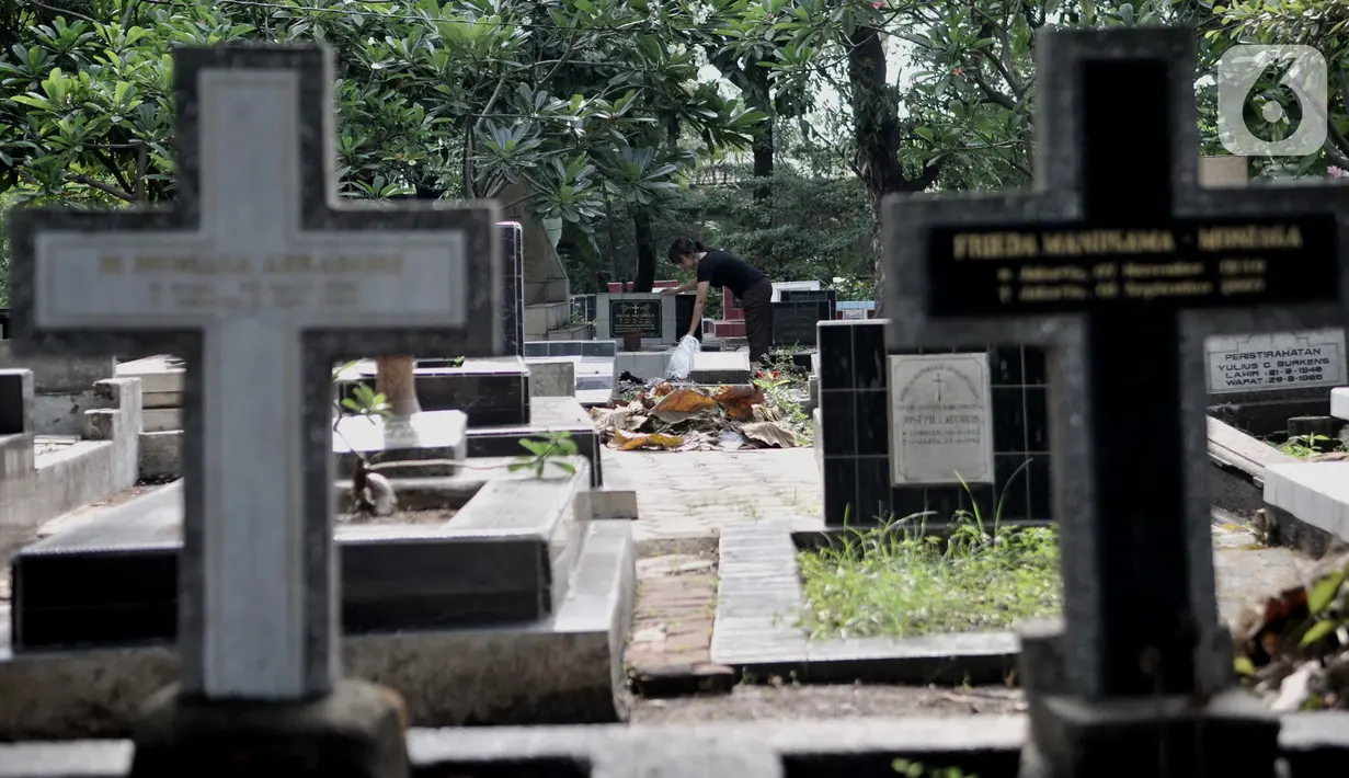 Keluarga membersihkan makam saat ziarah di kompleks pemakaman Gereja Tugu, Semper, Jakarta, Senin (23/12/2019). Ziarah menjadi tradisi keluarga keturunan Portugis di Kampung Tugu menjelang Hari Raya Natal. (merdeka.com/Iqbal Nugroho)