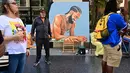 Artis Mohammed Mubarak berdiri di samping karya seni mendiang rapper AS Nipsey Hussle saat orang-orang berkumpul untuk upacara Anumerta Hollywood Walk of Fame Star Hussle di Hollywood, California (15/8/2022). (AFP/Frederic J. Brown)