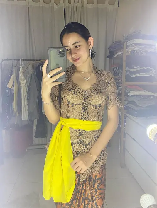 Dalam sebuah foto mirror selfie yang diunggahnya di Instagramnya, Laura Theux juga terlihat mengenakan kebaya bernuansa cokelat, lengkap dengan selendang kuningnya dan kain sebagai bawahan. Foto: Instagram.