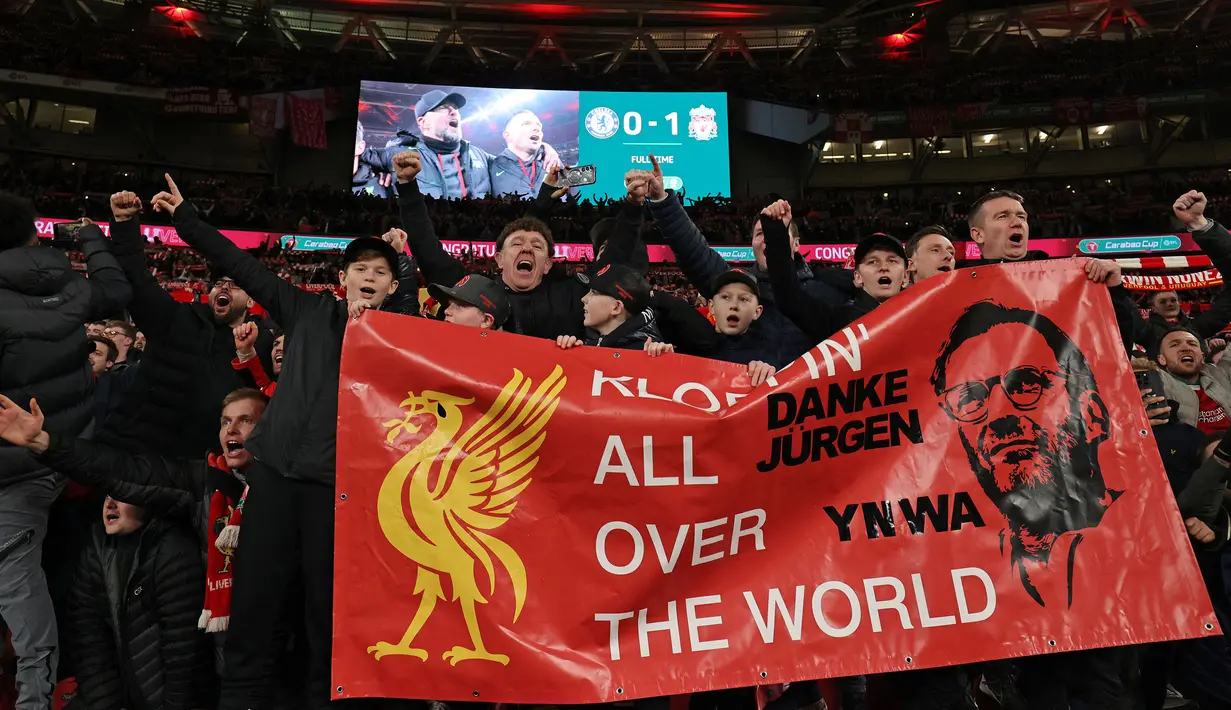 Para suporter Liverpool membentangkan banner sambil bernyanyi setelah laga final Carabao Cup 2023/2024 di Stadion Wembley, Inggris, Minggu (25/02/2024). The Reds menang atas Chelsea dengan skor 1-0 melalui gol Virgil Van Dijk pada menit ke-118. (AFP/Adrian Dennis)